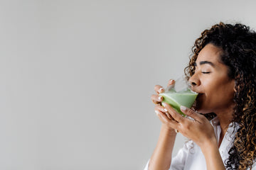 woman drinking a glass of matcha green tea