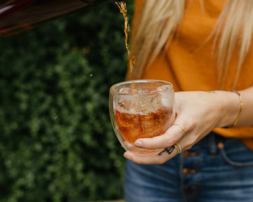 Amber colored tea being poured into a refreshing glass of iced tea